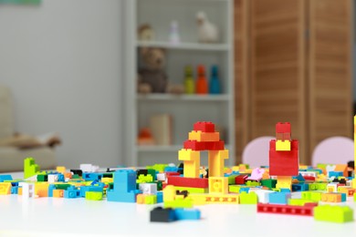 Photo of Construction toy. Figures made with building bricks and colorful blocks on white table indoors