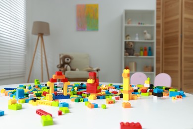 Photo of Construction toy. Figures made with building bricks and colorful blocks on white table indoors