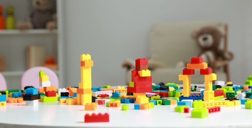 Photo of Construction toy. Figures made with building bricks and colorful blocks on white table indoors