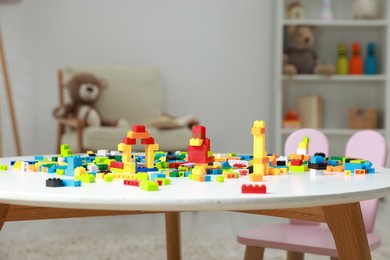 Photo of Construction toy. Figures made with building bricks and colorful blocks on white table indoors