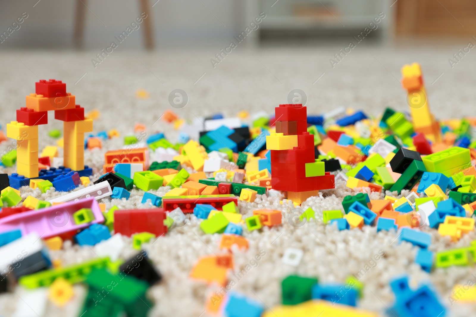 Photo of Construction toy. Figures made with building bricks and colorful blocks on floor indoors, closeup