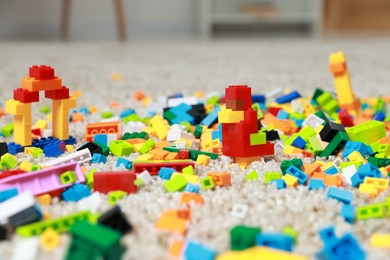 Photo of Construction toy. Figures made with building bricks and colorful blocks on floor indoors, closeup