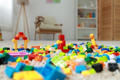 Photo of Construction toy. Figures made with building bricks and colorful blocks on floor indoors, closeup