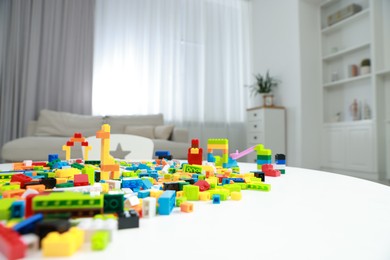 Photo of Construction toy. Figures made with building bricks and colorful blocks on white table indoors, closeup. Space for text