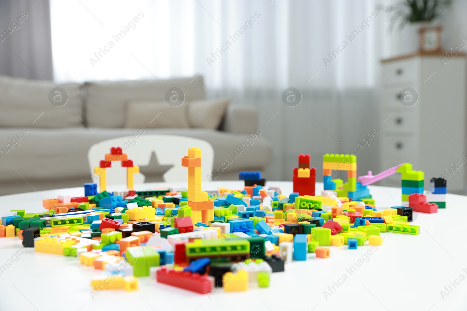 Photo of Construction toy. Figures made with building bricks and colorful blocks on white table indoors, closeup