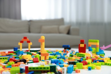 Photo of Construction toy. Figures made with building bricks and colorful blocks on table indoors, closeup