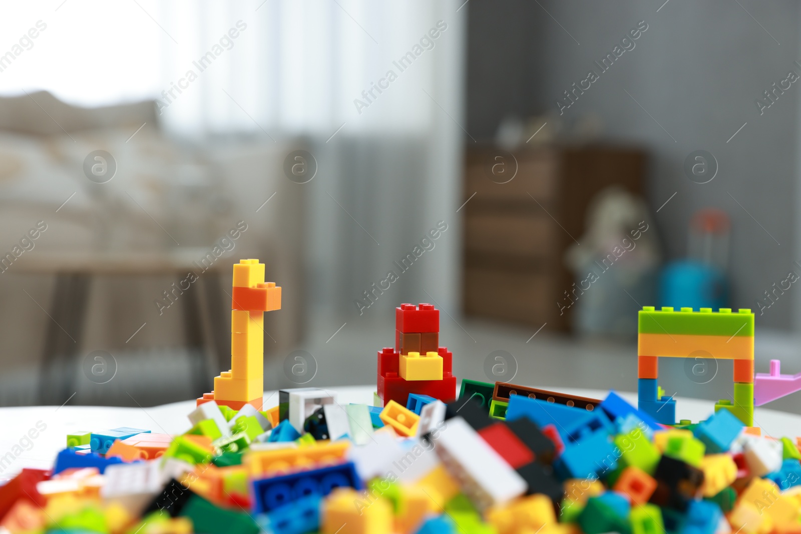 Photo of Construction toy. Figures made with building bricks and colorful blocks on table indoors, closeup