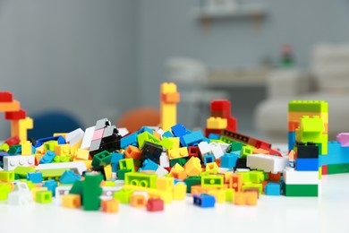 Photo of Construction toy. Colorful building blocks on white table indoors, closeup