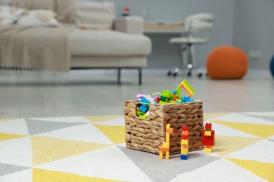 Photo of Construction toy. Figures made with building bricks and wicker basket of blocks on floor indoors, space for text