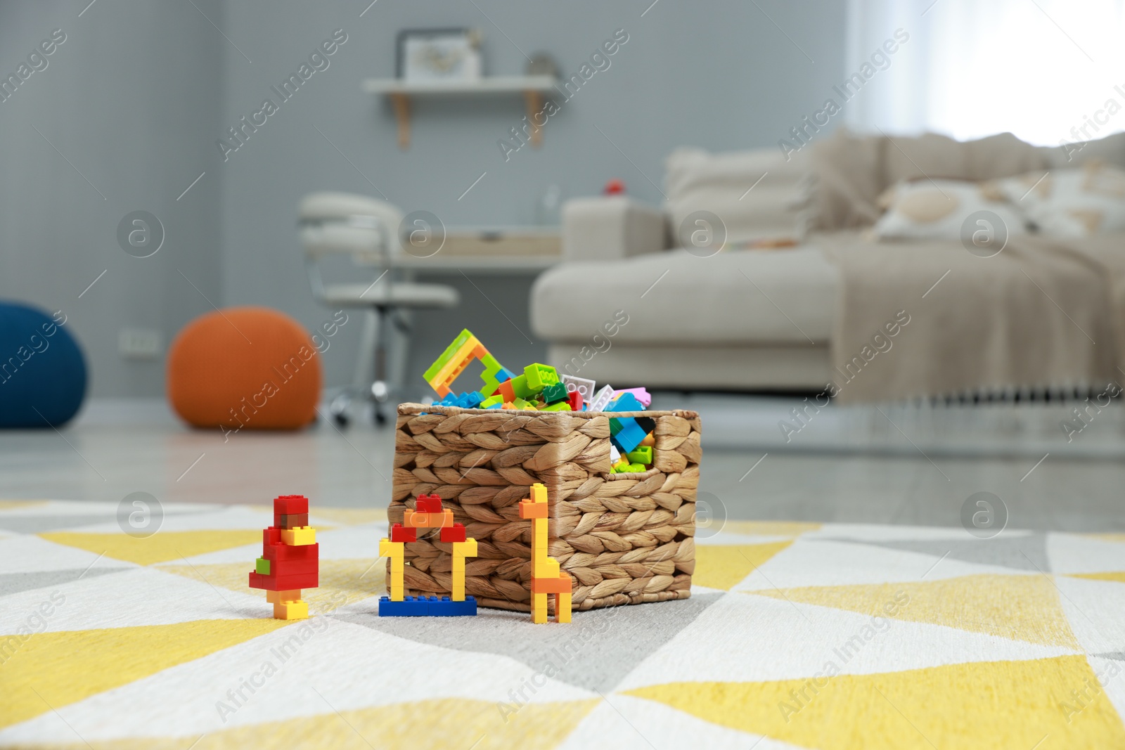 Photo of Construction toy. Figures made with building bricks and wicker basket of blocks on floor indoors