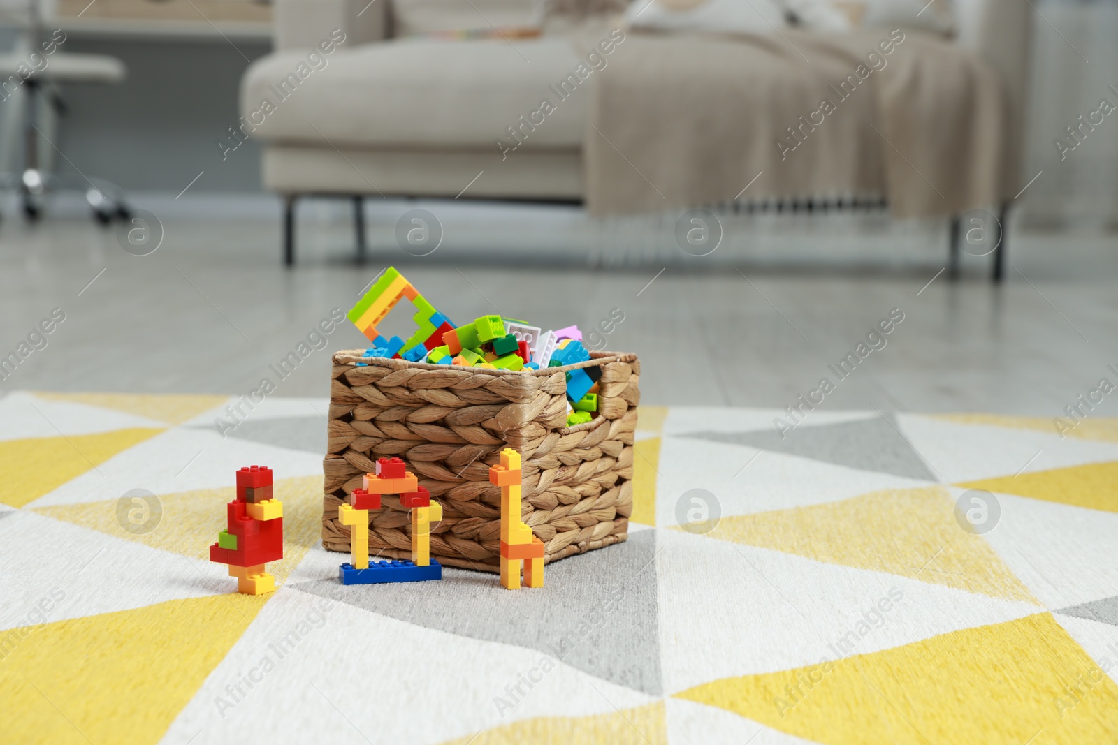 Photo of Construction toy. Figures made with building bricks and wicker basket of blocks on floor indoors, space for text