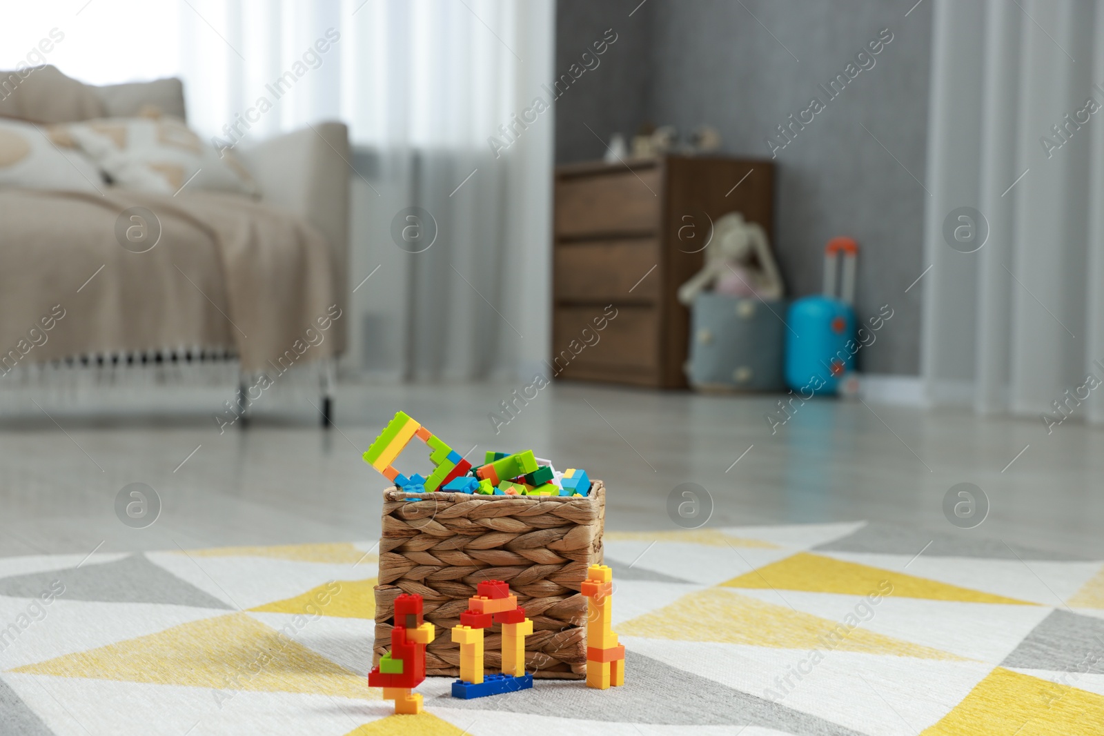 Photo of Construction toy. Figures made with building bricks and wicker basket of blocks on floor indoors