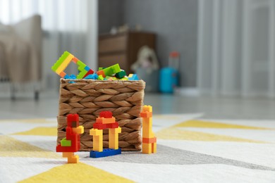 Photo of Construction toy. Figures made with building bricks and wicker basket of blocks on floor indoors, space for text