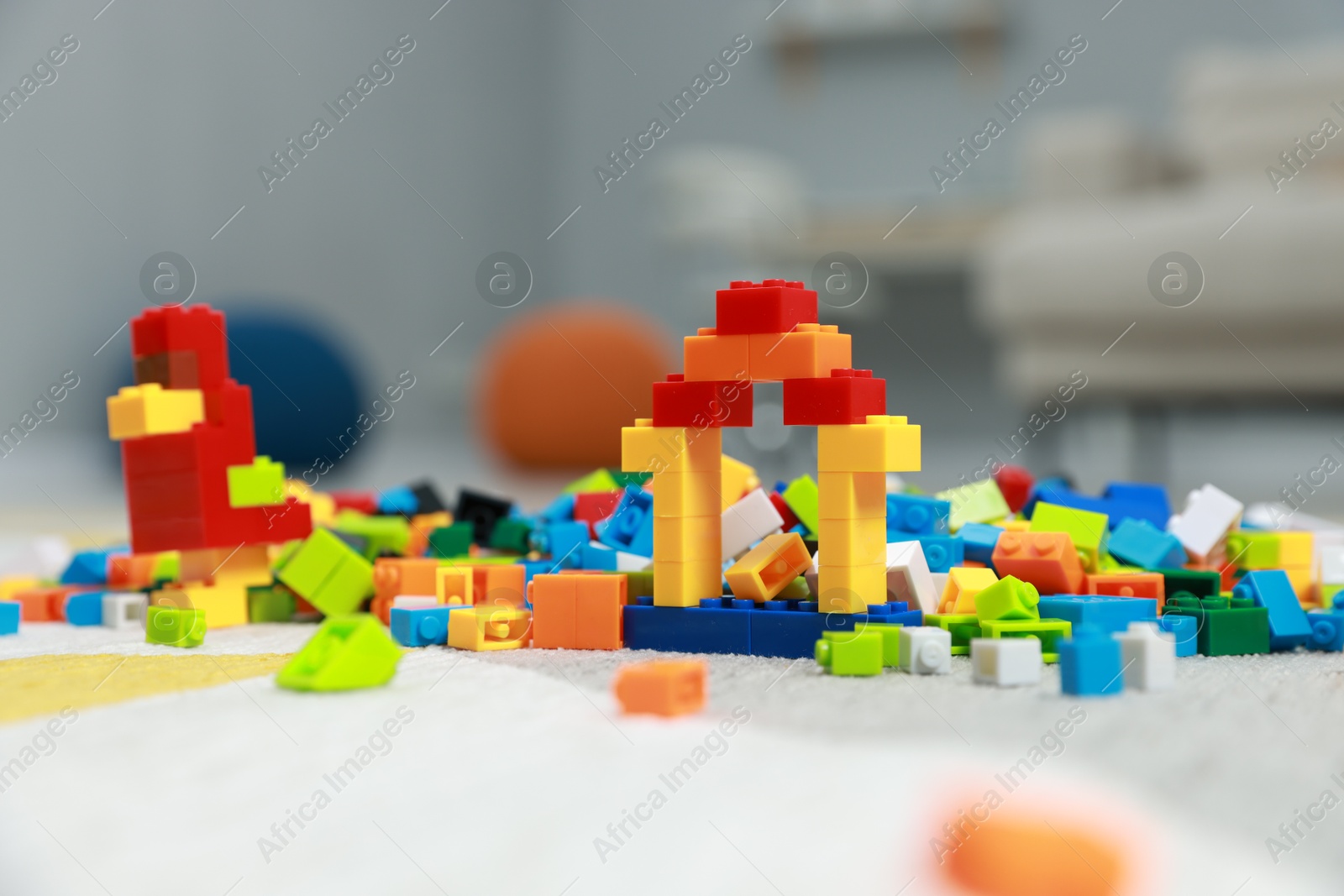 Photo of Construction toy. Figures made with building bricks and colorful blocks on floor indoors, closeup