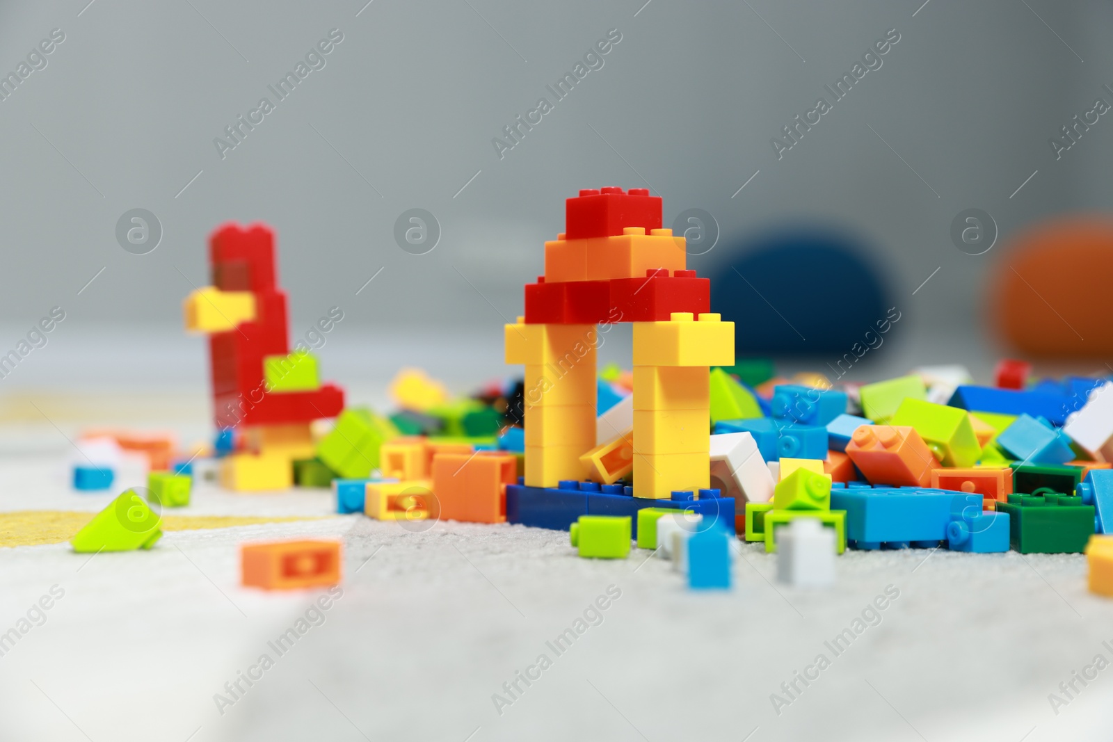 Photo of Construction toy. Figures made with building bricks and colorful blocks on floor indoors, closeup