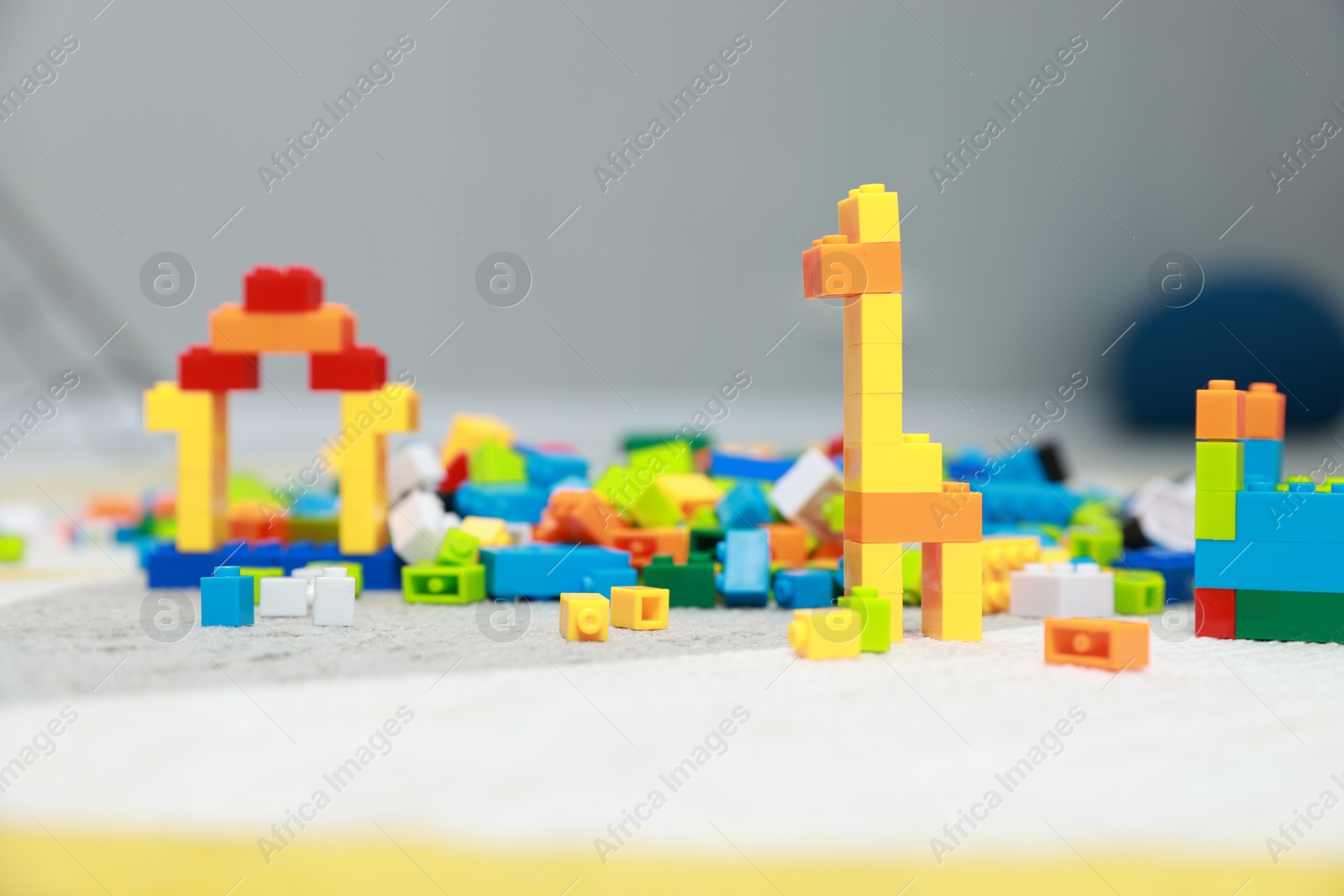 Photo of Construction toy. Figures made with building bricks and colorful blocks on floor indoors, closeup