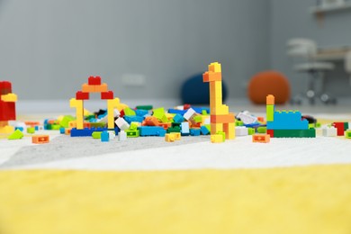 Photo of Construction toy. Figures made with building bricks and colorful blocks on floor indoors