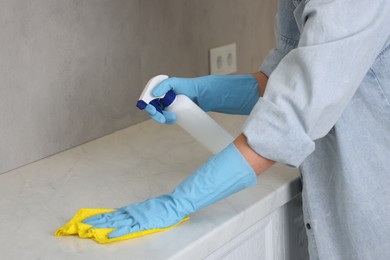 Photo of Woman using cleaning product while wiping countertop with rag indoors, closeup. Space for text