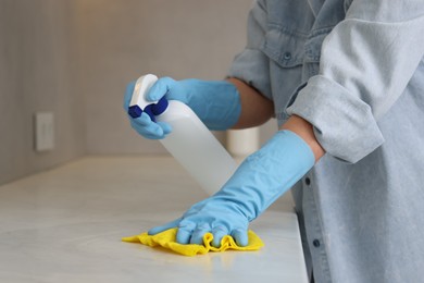 Photo of Woman using cleaning product while wiping countertop with rag indoors, closeup. Space for text