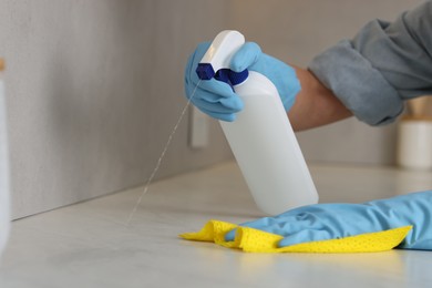 Photo of Woman using cleaning product while wiping countertop with rag indoors, closeup. Space for text