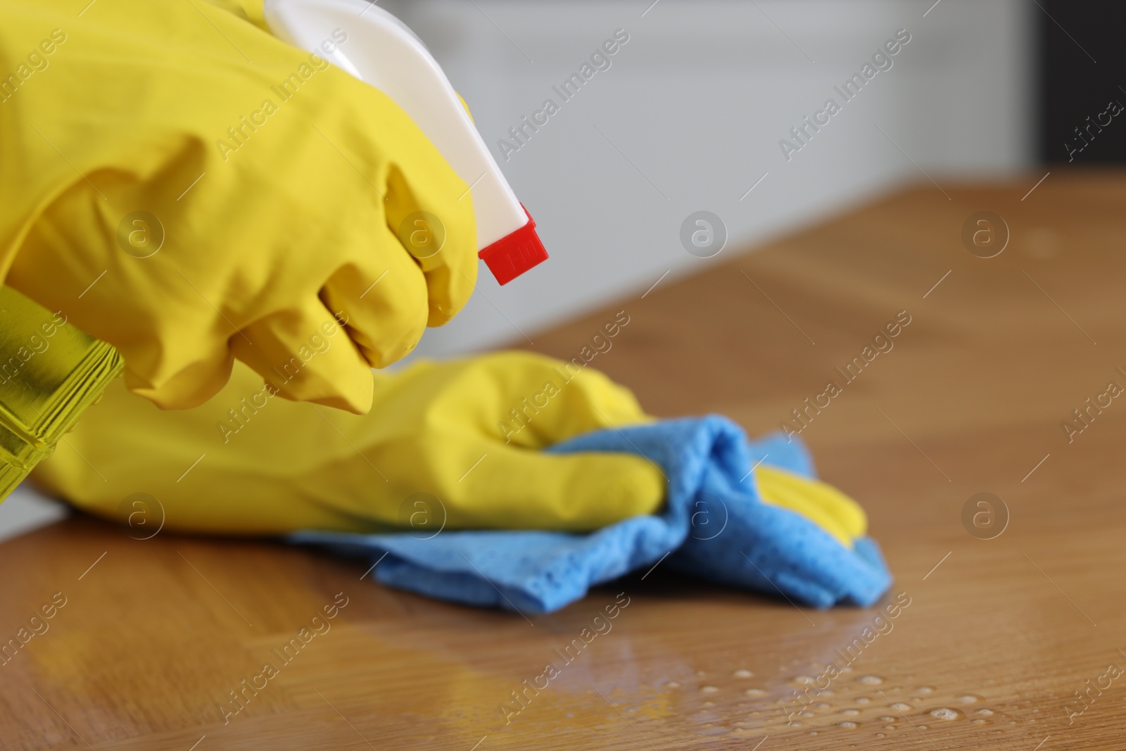 Photo of Woman using cleaning product while wiping wooden table with rag indoors, closeup. Space for text