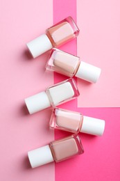 Photo of Nail polishes in bottles on color background, flat lay