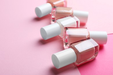 Photo of Nail polishes in bottles on color background, closeup