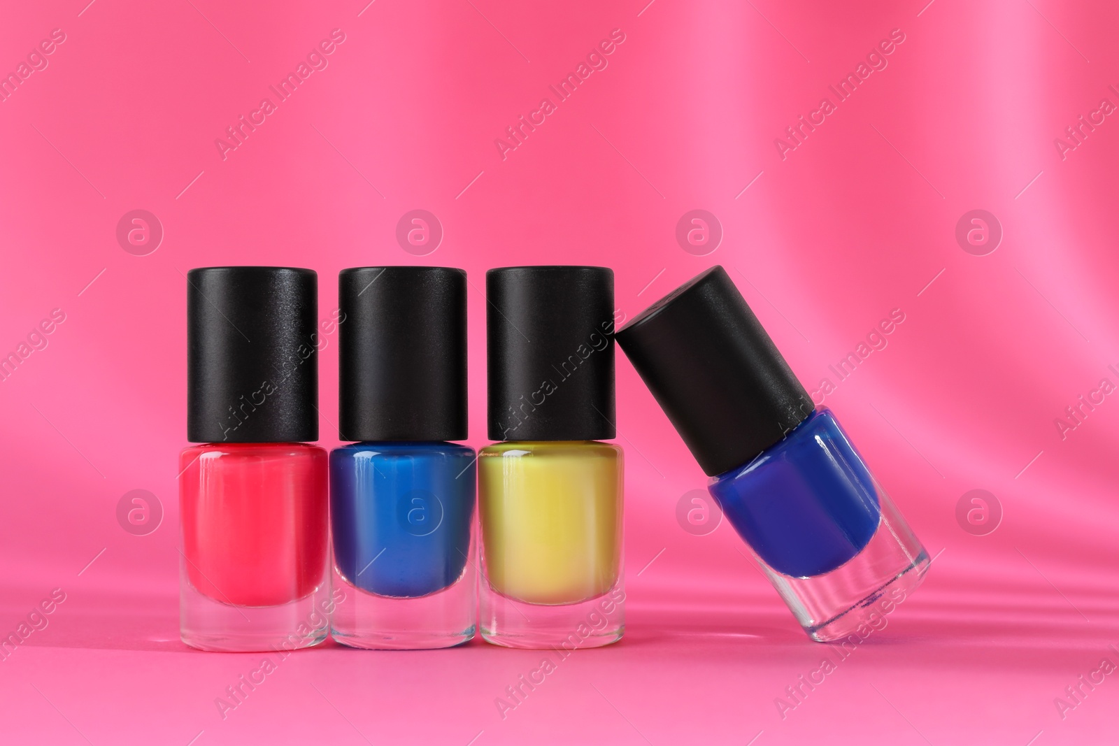 Photo of Nail polishes in bottles on pink background