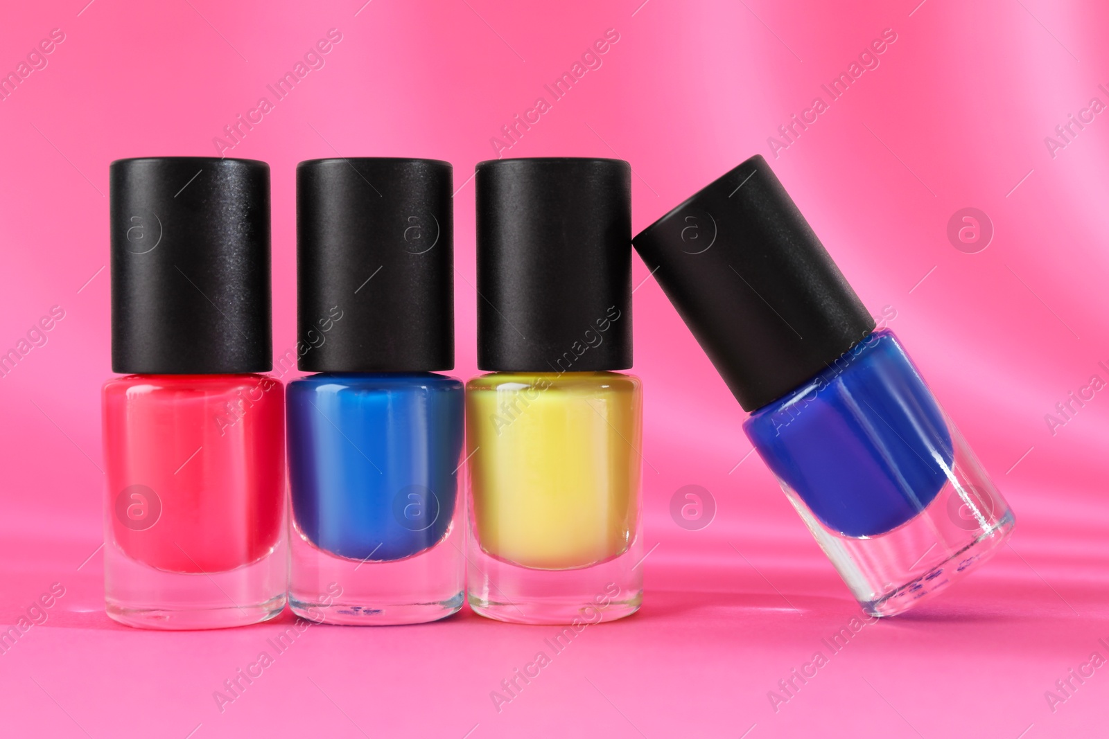 Photo of Nail polishes in bottles on pink background