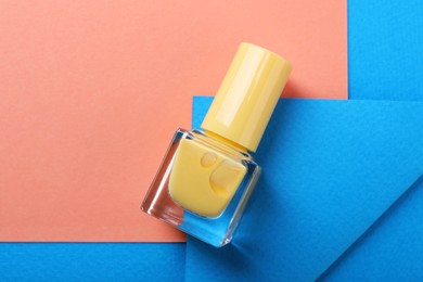 Photo of Nail polish in bottle on color background, top view