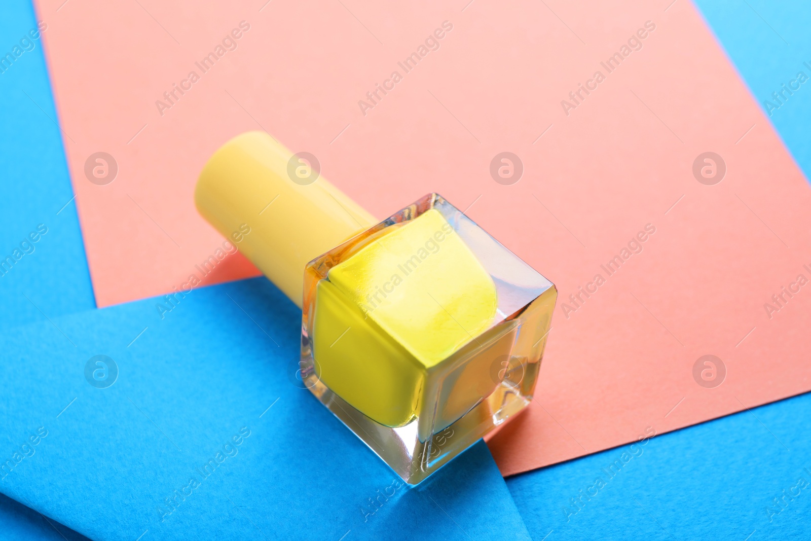 Photo of Nail polish in bottle on color background, closeup