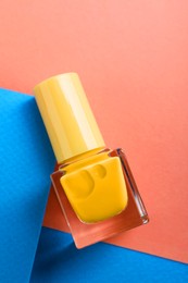 Photo of Nail polish in bottle on color background, top view