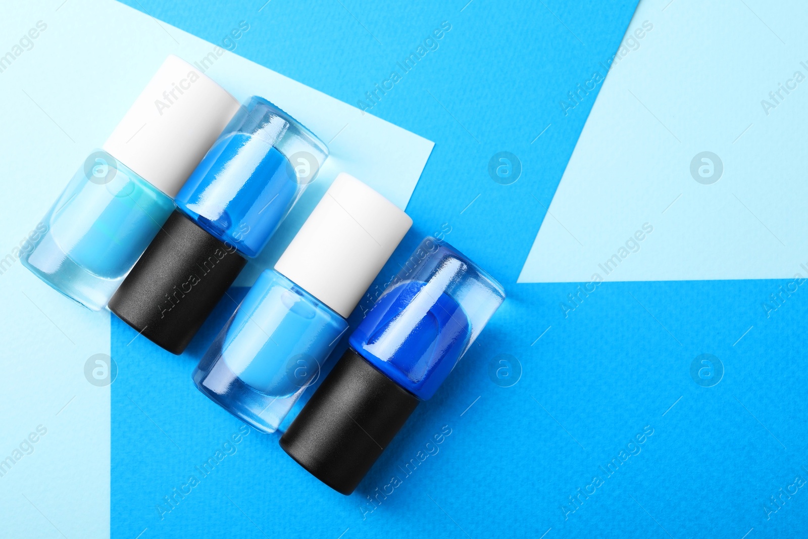 Photo of Nail polishes in bottles on color background, flat lay. Space for text