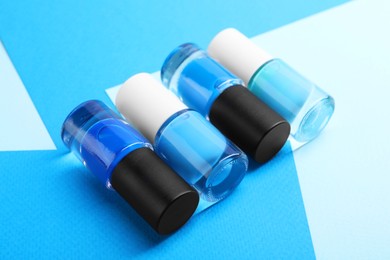 Photo of Nail polishes in bottles on color background, closeup