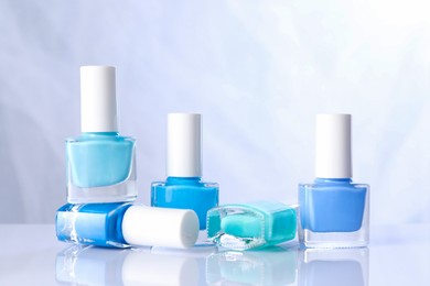 Photo of Set of nail polishes in bottles on mirror table against white background