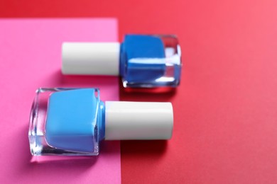 Photo of Nail polishes in bottles on color background, closeup. Space for text