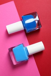 Photo of Bright nail polishes in bottles on color background, flat lay