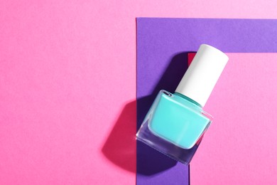 Photo of Nail polish in bottle on color background, top view. Space for text