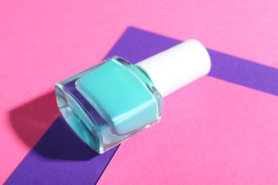 Photo of Nail polish in bottle on color background, closeup