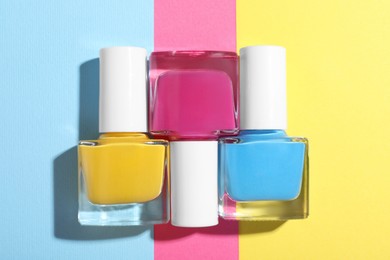 Photo of Bright nail polishes in bottles on color background, flat lay