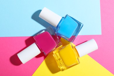 Photo of Bright nail polishes in bottles on color background, flat lay