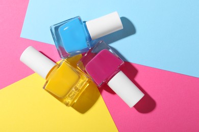 Photo of Bright nail polishes in bottles on color background, flat lay