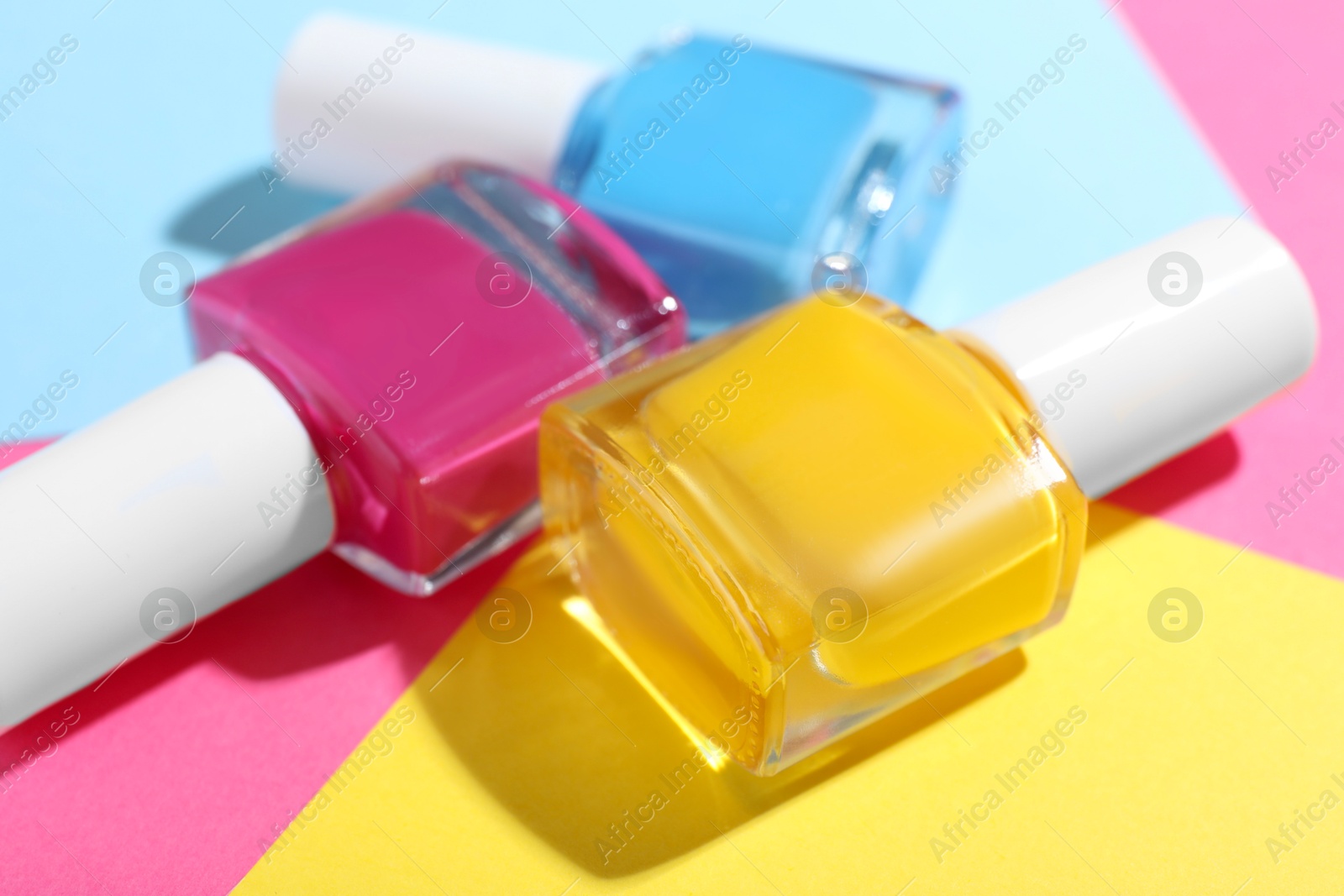 Photo of Bright nail polishes in bottles on color background, closeup