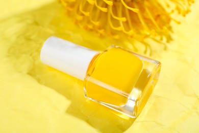 Photo of Nail polish in bottle on yellow background, closeup