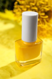 Photo of Nail polish in bottle on yellow background, closeup