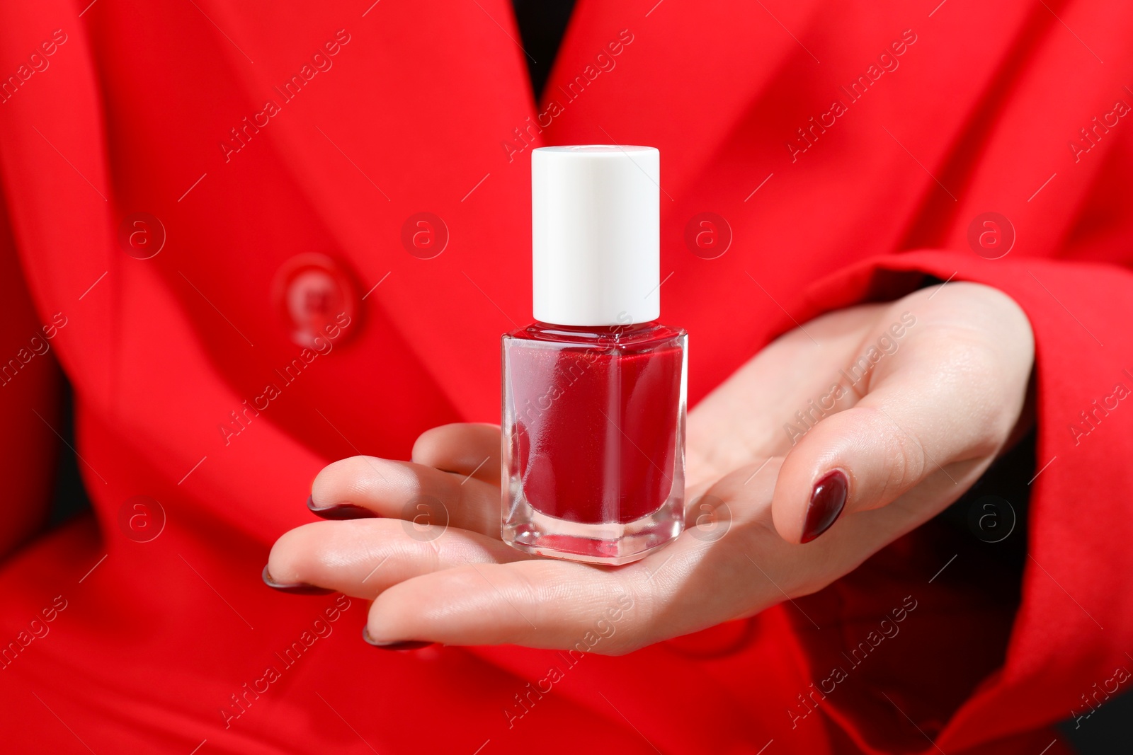 Photo of Woman holding bottle with red nail polish, closeup