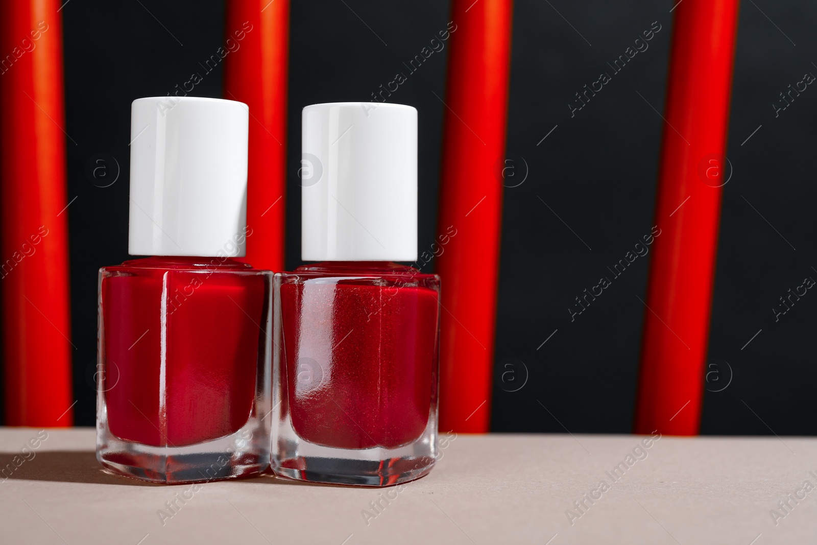 Photo of Red nail polishes in bottles on white table, closeup. Space for text