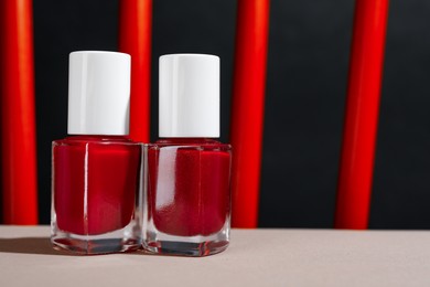 Photo of Red nail polishes in bottles on white table, closeup. Space for text