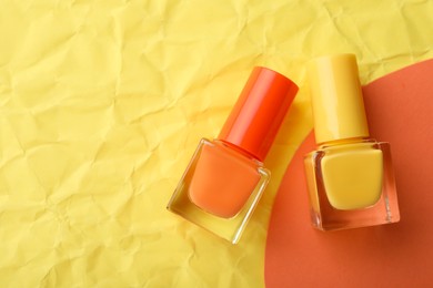 Photo of Nail polishes in bottles on color background, flat lay. Space for text