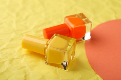 Photo of Nail polishes in bottles on color background, closeup